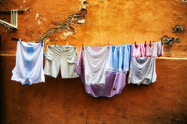White T-shirt dries on clothesline in open air in attic of residential building. Urban housing, everyday life concept