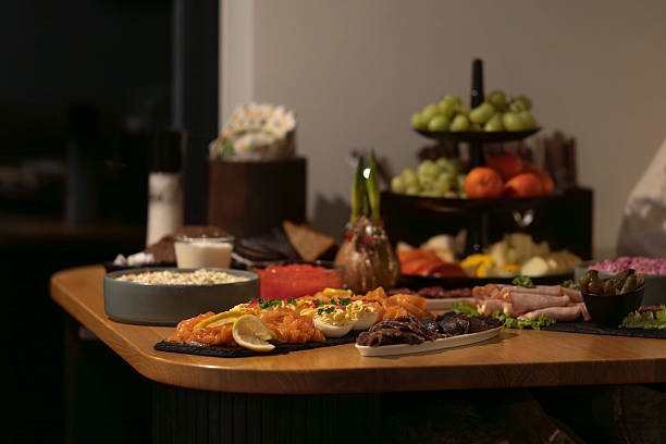 istock Elegant catering buffet with smoked salmon, cold cuts, devilled eggs, and fresh fruit arranged on a wooden table. 2254269849