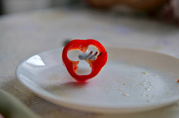 Close-up of Red Bell Pepper Slice on a Fork over White Plate