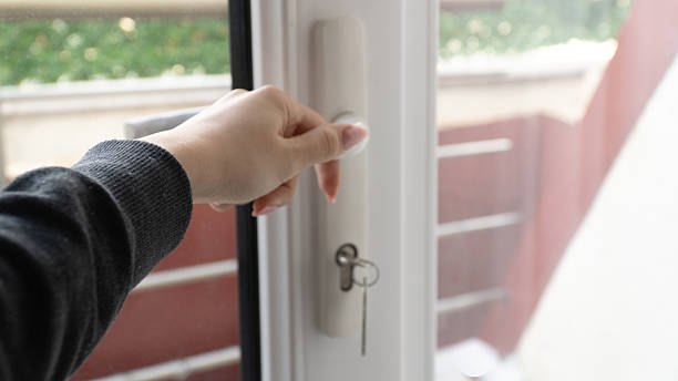 istock Woman's hand opening or locking a white PVC window with a key. 2254271336