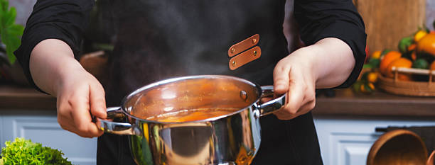 istock Chef holding steaming pot with pumpkin soup in bright home kitchen, freshly prepared dish among seasonal vegetables for healthy recipe visuals and warm culinary lifestyle content creation. 2254277033