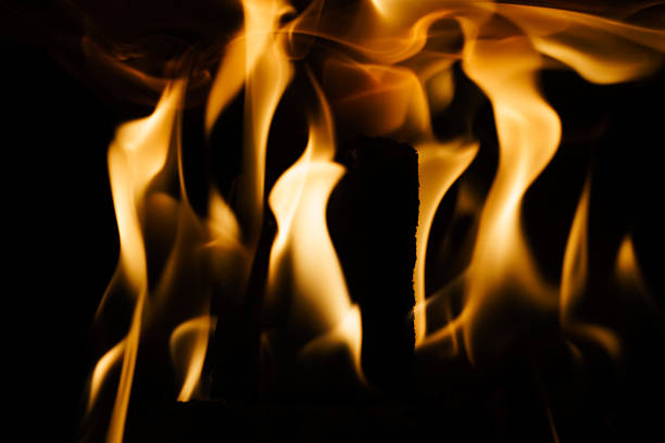 Close-up of a fire in a fireplace, against a black background