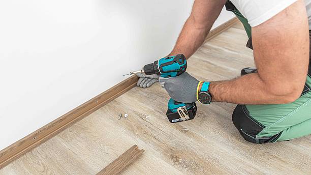 istock Installing elegant plastic baseboard, showcasing skilled craftsmanship in home improvement and renovation. Worker using a screwdriver to mount skirting board, plinth. 2254279386