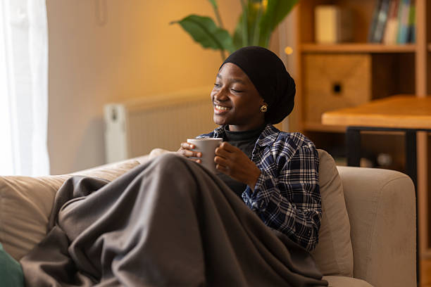 istock Young woman enjoying warm drink wrapped in blanket 2254279999
