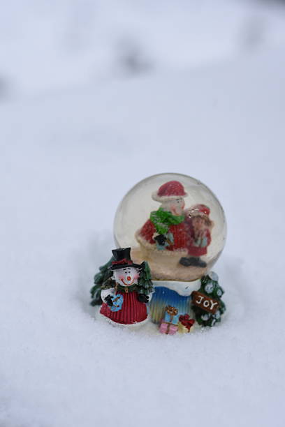Minimal vertical composition featuring a Christmas snow globe with Santa Claus and snowman. Clean white winter background, festive holiday concept.