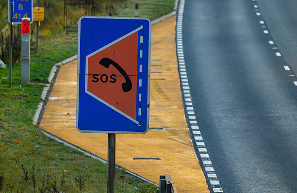 Emergency Refuge on a UK Smart motorway where no hard shoulder exists. SOS and Telephone sign in front of the ERA. Refuge area painted yellow.