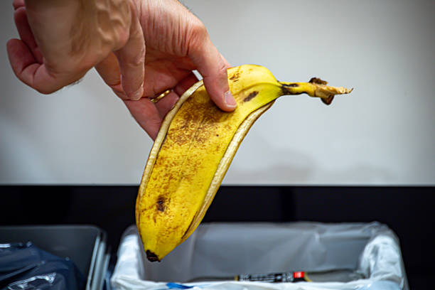 istock Hand Disposing Banana Peel in Trash Bin 2254296262