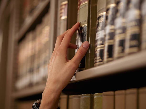 A hand is reaching for a book on a library shelf, showcasing a serene and focused atmosphere in an elegant, educational setting.