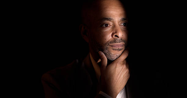 African American man contemplating in a studio with dramatic lighting