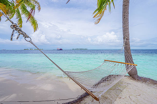 Hammock hanging between two coconut palm trees on the tropical beach
