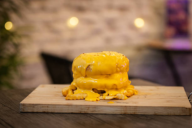 Hamburger is serving with cheddar cheese and french fries on fast food restaurant table.