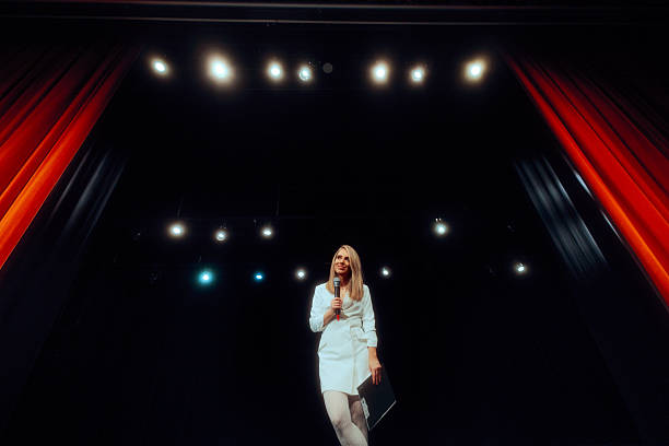 istock Show Presenter on Stage Holding Microphone and Clipboard 2254311572