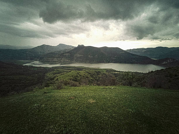 Mountain river in lush green scenic nature landscape under dark storm clouds. Biodiversity protection, sustainable resource, water conservation & environmental regeneration
