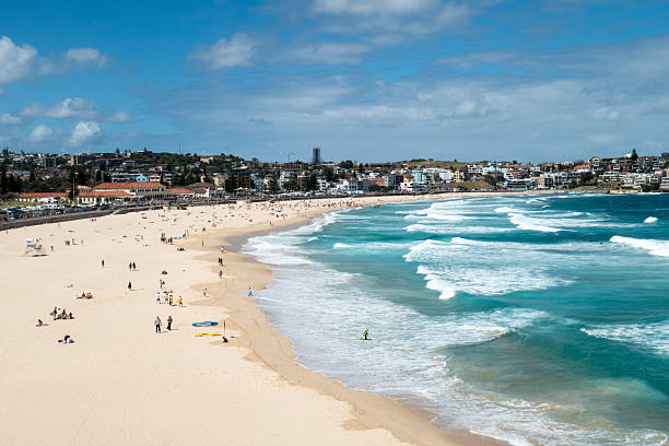 Waves break at Bondi Beach on Sunday, 28 December 2025 in the eastern suburbs of Sydney. Normally more crowded at this time of year because of summer holidays, numbers dropped after the terrorist attack on the Jewish community in Archer Park two weeks earlier. That park is located just after the Bondi Pavilion, which is the large building in the central waterfront. This image was taken from the southern cliffs on a hot, sunny and windy afternoon on 28 December 2025.