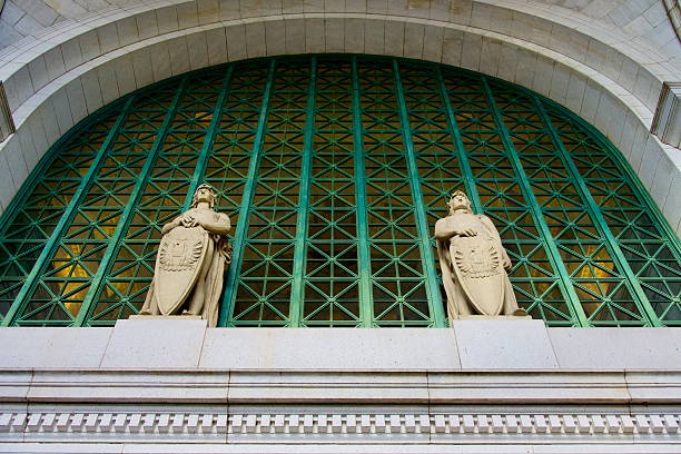 Washington, D.C., USA - December 14, 2025: Two statues appear vigilant atop the main entrance to Washington Union Station as unseen passengers enter beneath.
