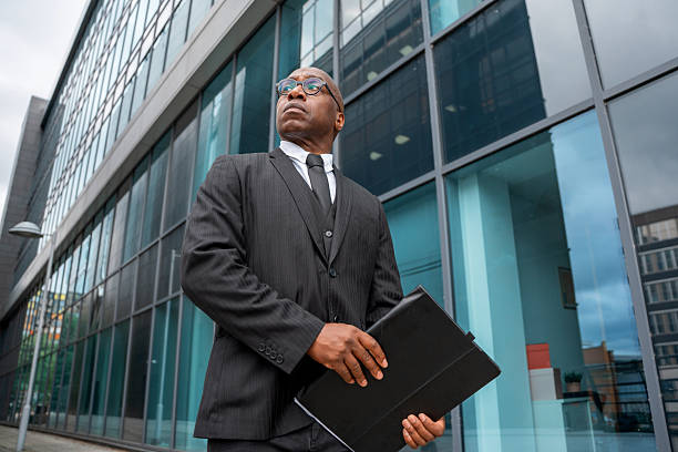 istock Businessman stands outside modern building while holding a folder during a cloudy day 2254319997