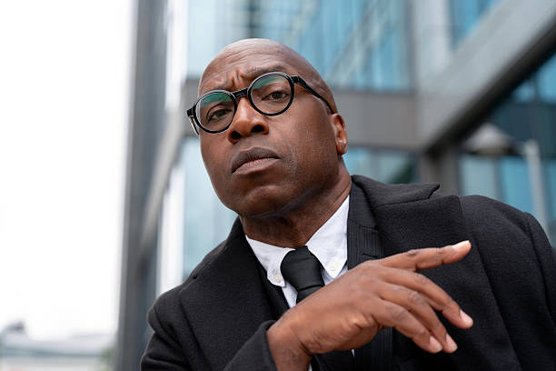 istock Man in suit standing outside modern building with glasses looking serious and pointing 2254320093