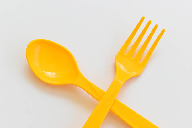 yellow spoon and fork isolated on white background, plastic cutlery for picnic