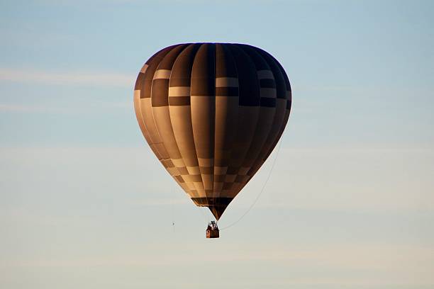 hot air balloon mid air at dusk with a white cloud background.