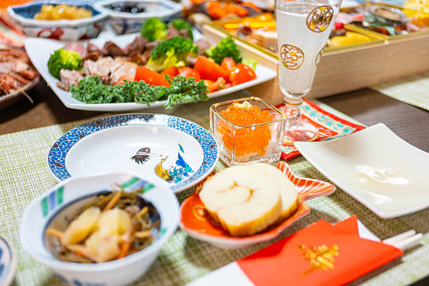 A traditional Japanese New Year’s feast featuring beautifully arranged osechi ryori in lacquered boxes, served on a festive dining table. The image showcases a variety of seasonal dishes symbolizing prosperity, health, and happiness, commonly enjoyed during the Japanese New Year celebration.