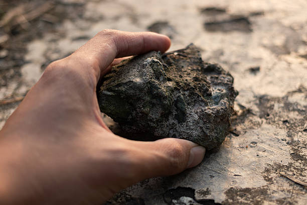 istock Hand holding rough stone over cracked ground 2254328089