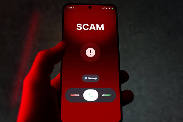 istock Hand holding smartphone with scam warning and call options on red screen 2254328934