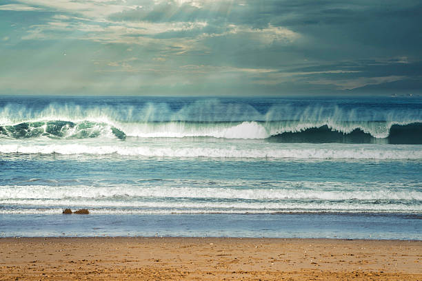 A tranquil beach scene with rolling ocean waves under a softly lit sky, capturing blue tones, sandy shore, and a gentle breeze perfect for nature or travel themes.