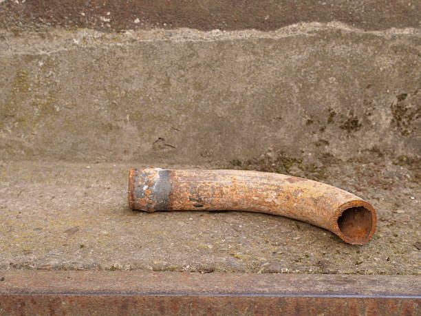 istock Rusty curved metal pipe on concrete steps. Aged industrial object with corrosion and time marks. 2254337798