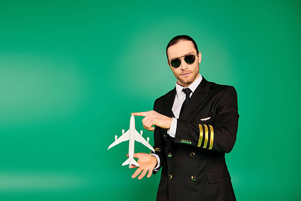 Confident man in a pilot uniform holds a model airplane, dressed for success in a lively space.