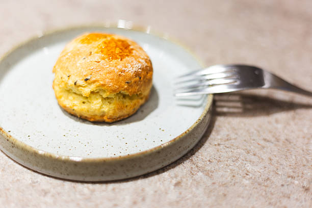 Freshly baked golden scones are elegantly arranged on textured ceramic plates, creating a warm afternoon tea atmosphere.