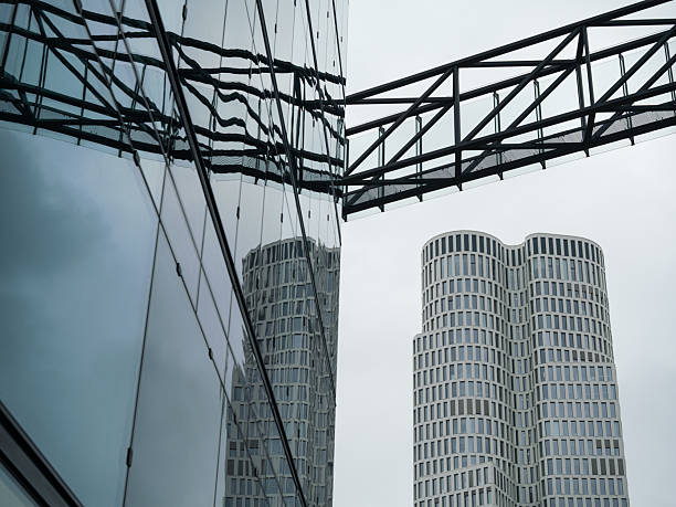 Curved Skyscraper Facade Reflected In Adjoining Office Tower and Steel Truss Bridge Connects Two Contrasting Glass Buildings, Berlin.