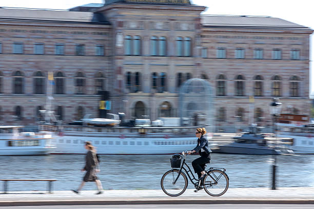 Stockholm, Sweden - June, 17, 2025:  Stockholm, Sweden - June, 17, 2025:  Scandinavian business woman on the bicycle in front of the Nationalmuseum in Stockholm. Panning photo.