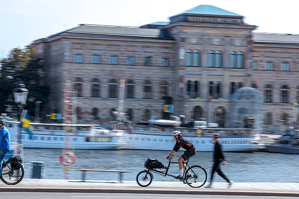Stockholm, Sweden - June, 17, 2025:  Scandinavian bicyclist and the pedestrian in front of the Nationalmuseum in Stockholm. Panning photo.