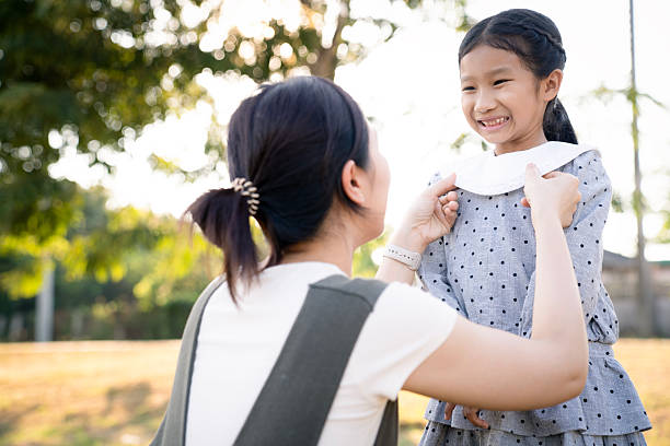 istock Asian mother caring for her smiling daughter outdoors in warm sunlight 2254346712