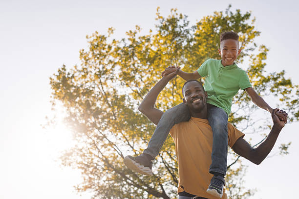 istock Elementary age boy having fun with his father outdoors, sitting on his shoulders 2254346950