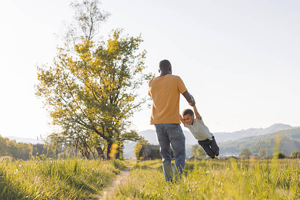 istock Dad playing with his son, holding his hands and spinning him around in a circle 2254346972