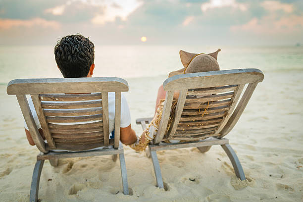 Lifestyle themes: Affectionate Hispanic couple sitting on the sand of a tropical island beach at sunset