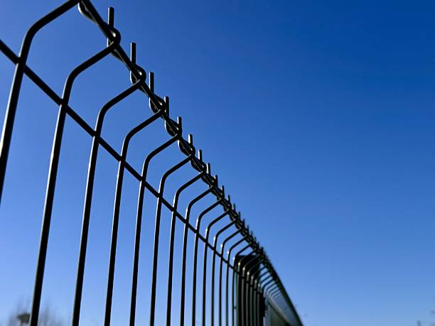 istock Industrial Fence Design, Contrasting Vibrant Colors Emphasize Security And Simplicity, Striking Geometric Pattern Of Metal Fence Highlights Boundaries Against Vivid Sky Background 2254353859