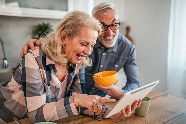istock Smiling mature couple having video call on digital tablet while eating breakfast cereal in kitchen 2254354758