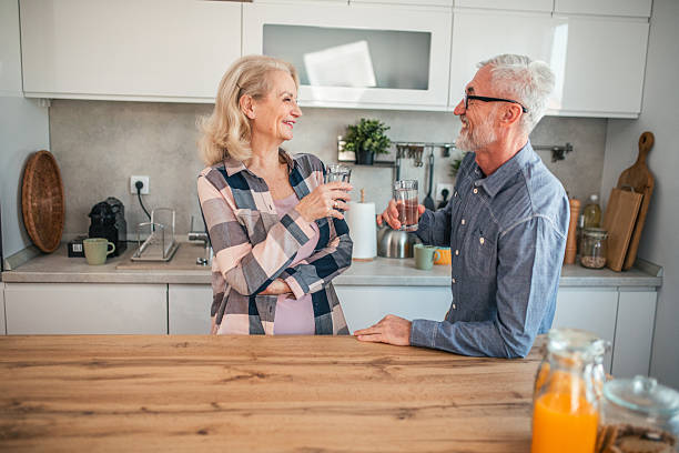 istock Smiling mature couple drinking water and chatting in kitchen 2254354810