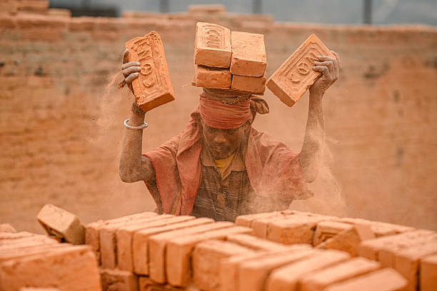 Migrant laborers balance bricks on their heads at a brick kiln in Bhaktapur, Nepal. Seasonal laborers from various parts of Nepal and India arrive during the winter season to work at kilns.