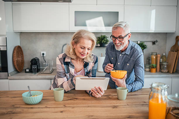 istock Senior couple having video call on digital tablet while eating breakfast cereal in kitchen 2254355025
