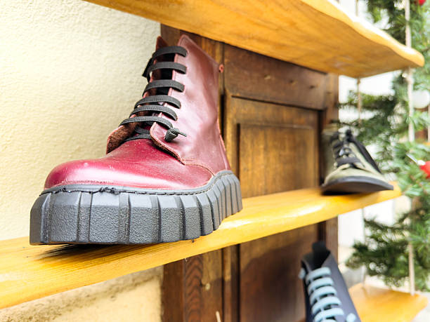 Stylish red leather boot on wooden shelf