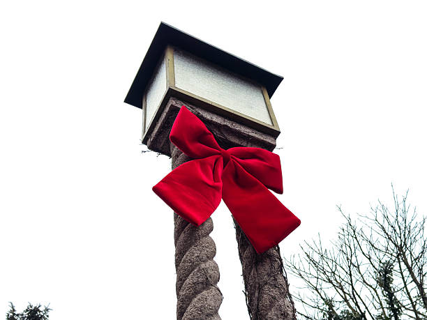 Large red ribbon bow on outdoor post amid winter trees
