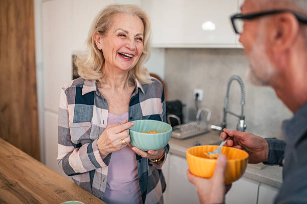istock Lovely senior couple eating cereal while standing at kitchen counter 2254356204