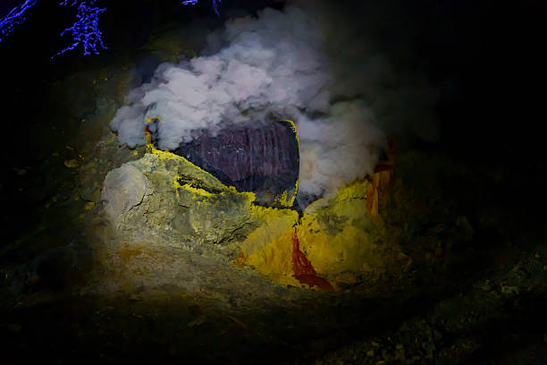 A female traveler wearing a face mask, hat, and backpack explores the rugged volcanic terrain of Kawah Ijen in East Java, Indonesia.