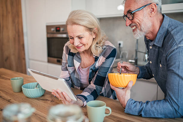 istock Carefree mature couple having video call on digital tablet while eating breakfast cereal in kitchen 2254357564