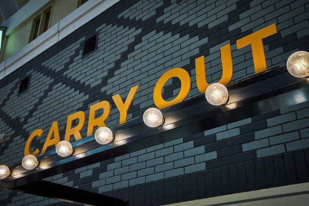 istock Modern Carry Out Sign on Brick Wall with Warm Night Lighting Low Angle 2254358447