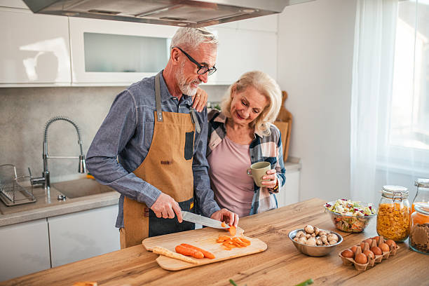 istock Mature man cooking lunch while woman drinks tea in kitchen 2254359776