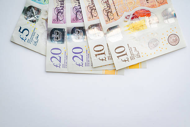 A group of British pound banknotes is fanned out across a white background, showing a mix of denominations with visible security features. The layout suggests themes of financial planning, income, or spending.